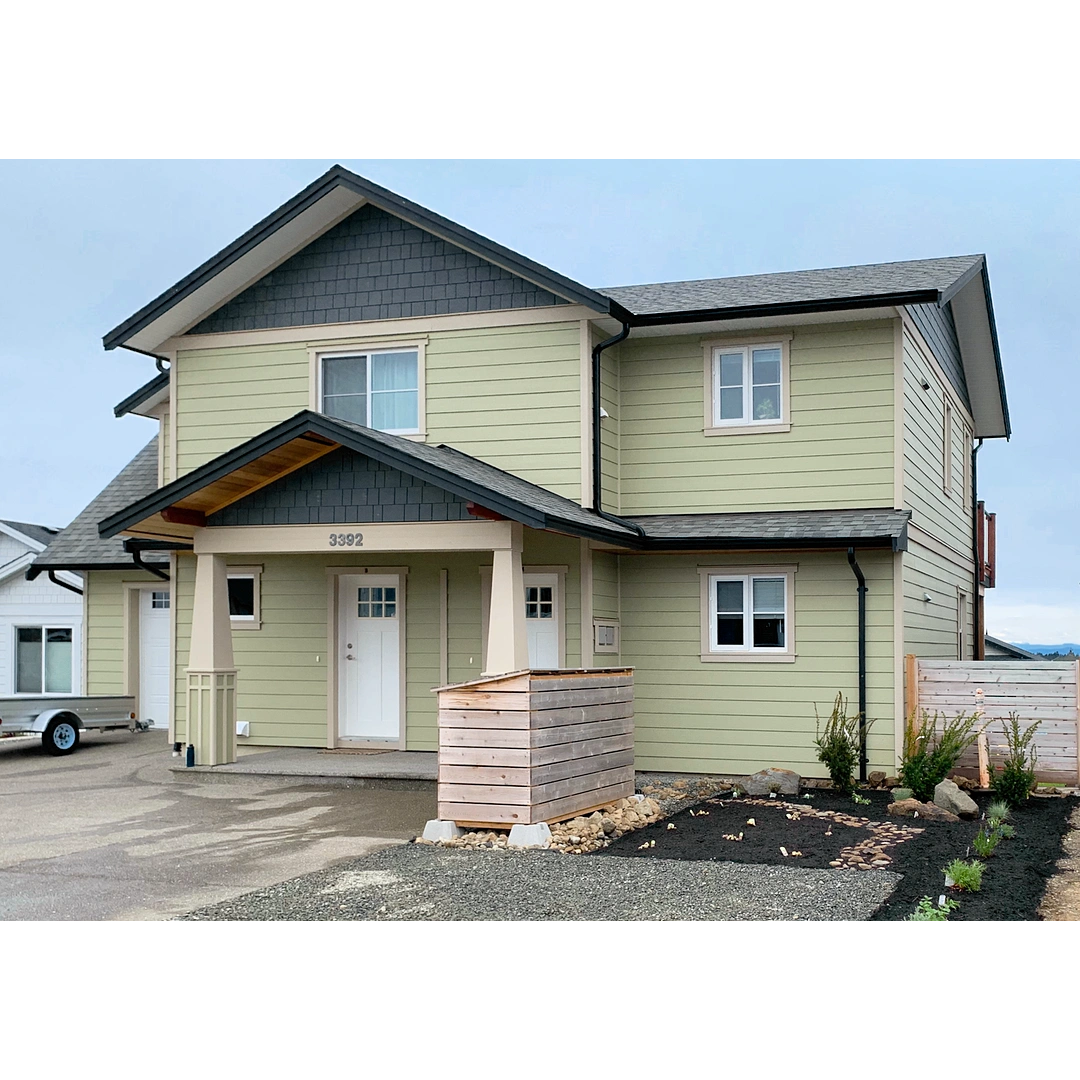 Craftsman style duplex with green siding and a garden