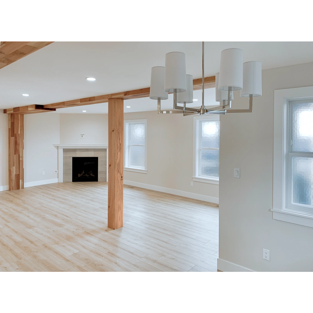 A large livingroom with a fireplace and a post and beam wrapped in laminated red cedar.